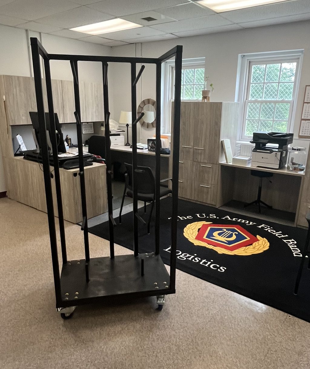 The finished black tube-steel rolling rack in the U.S. Army Field Band Logistics office, the Field Band logo rug behind it.