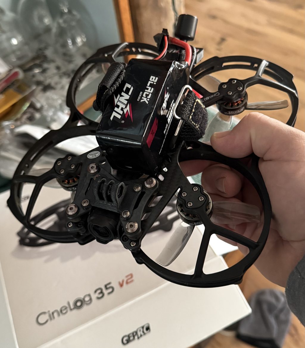 Hand holding a GEPRC CineLog 35 v2 cinewhoop FPV drone over its box.